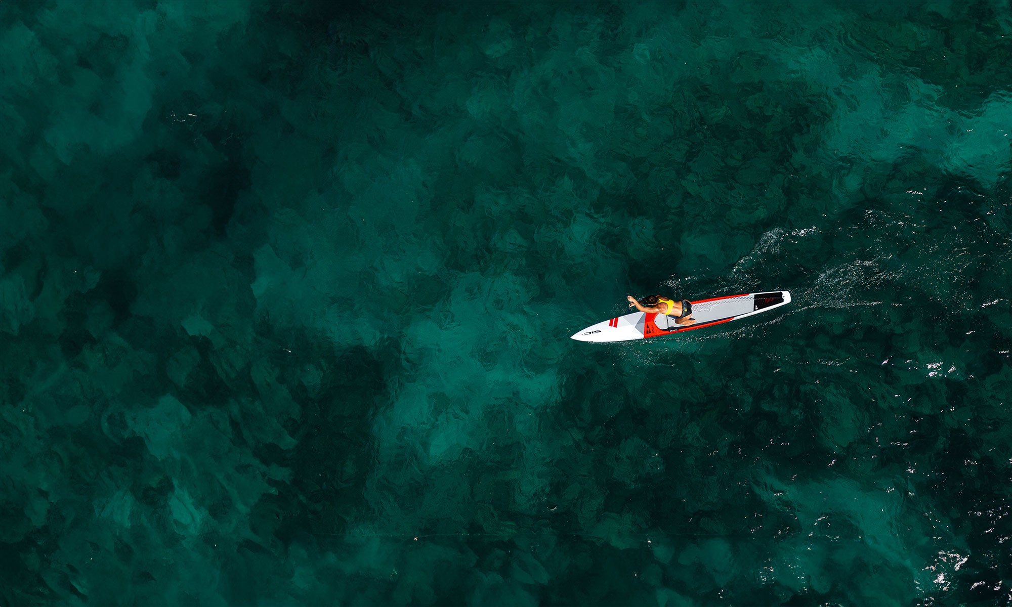 Person kayaking in clear blue water from an aerial perspective with a RST SUP of SICMAUI Brand