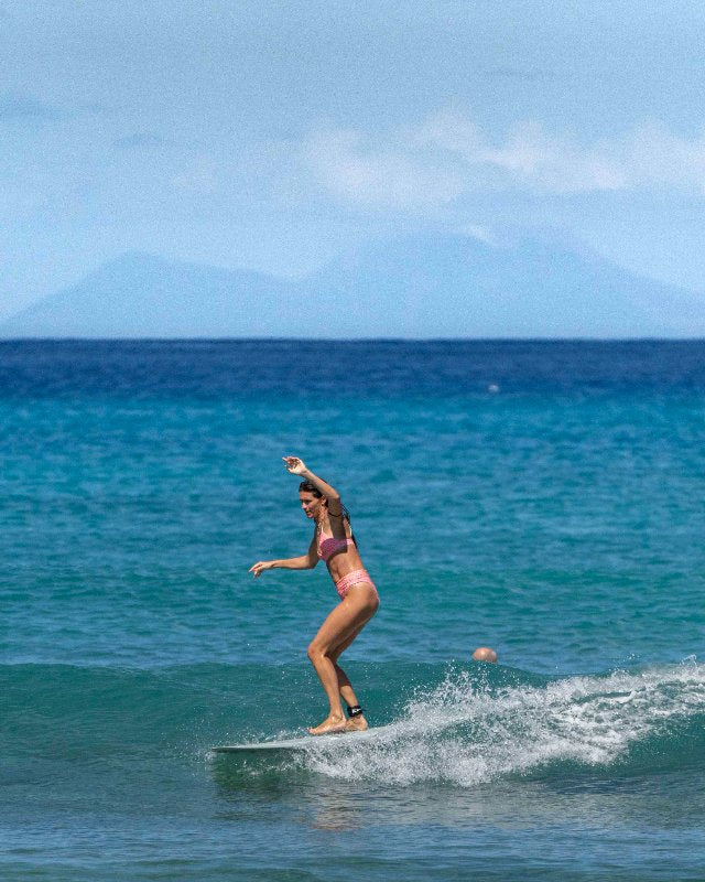 Person surfing on a wave with mountains in the background, surfgirl with a Smuggler longboard