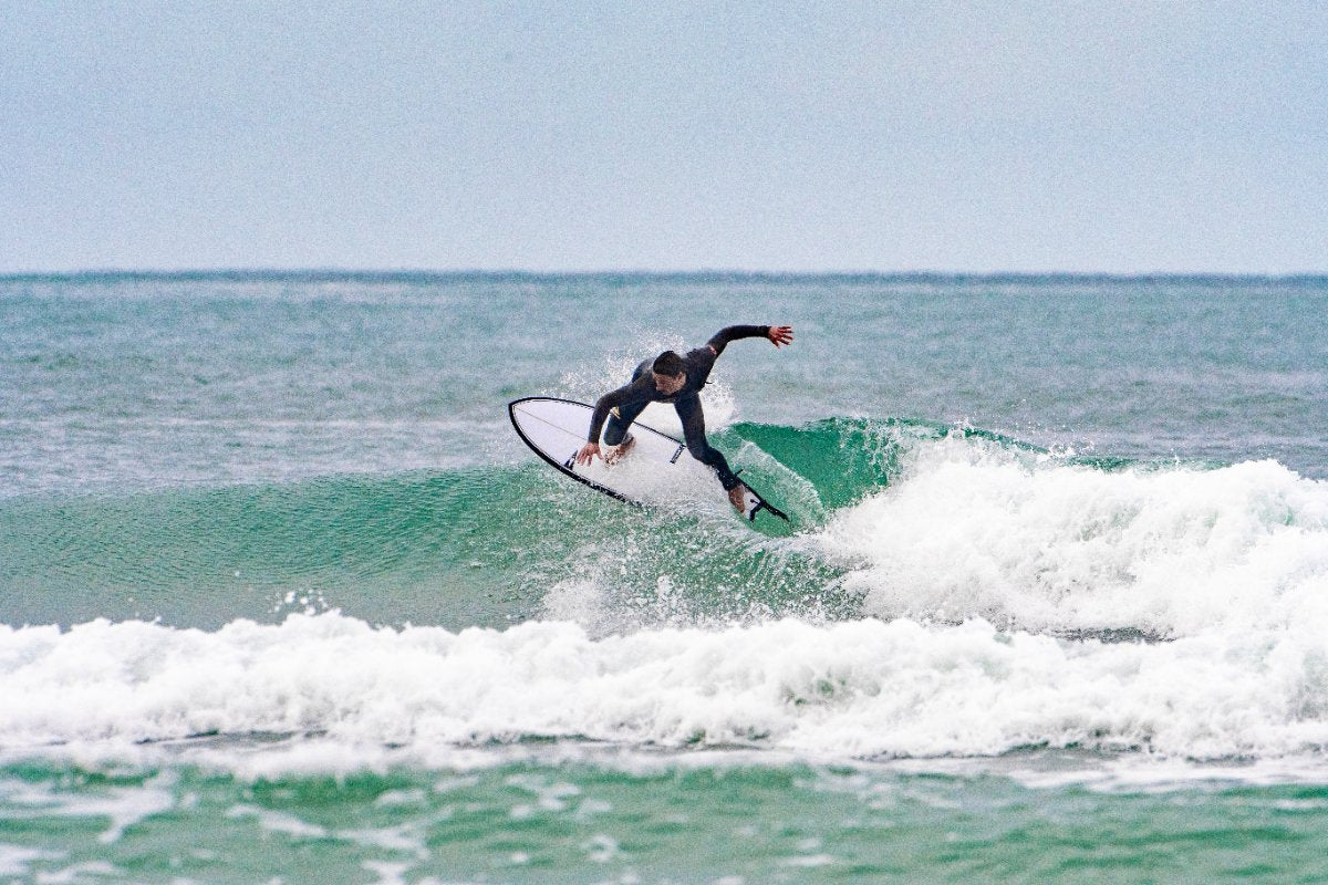 Person surfing on a wave in the ocean with a pistol whip shortboard of SIC MAUI brand.