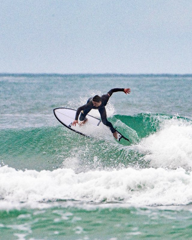 Person surfing on a wave in the ocean with a pistol whip shortboard of SIC MAUI brand.