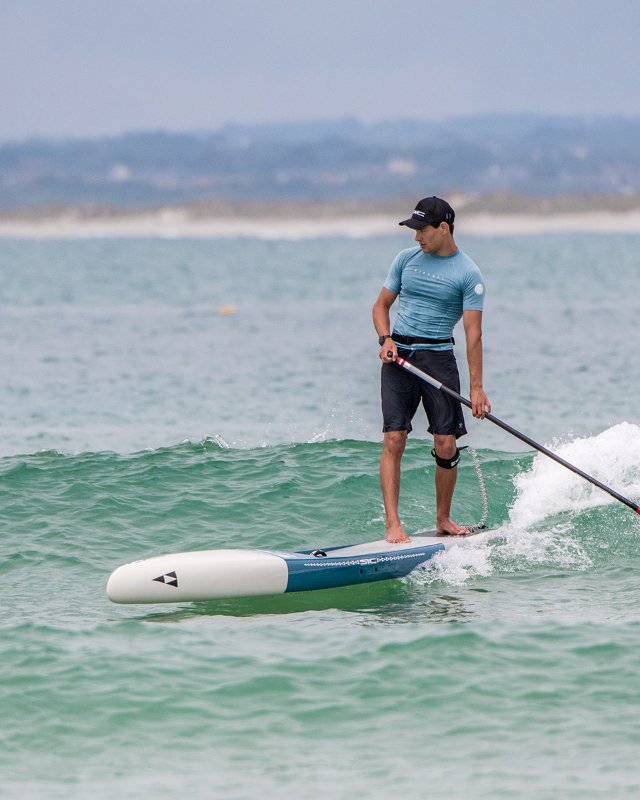 Action shot of a paddler navigating small ocean waves with a versatile SIC Maui all-around paddleboard.