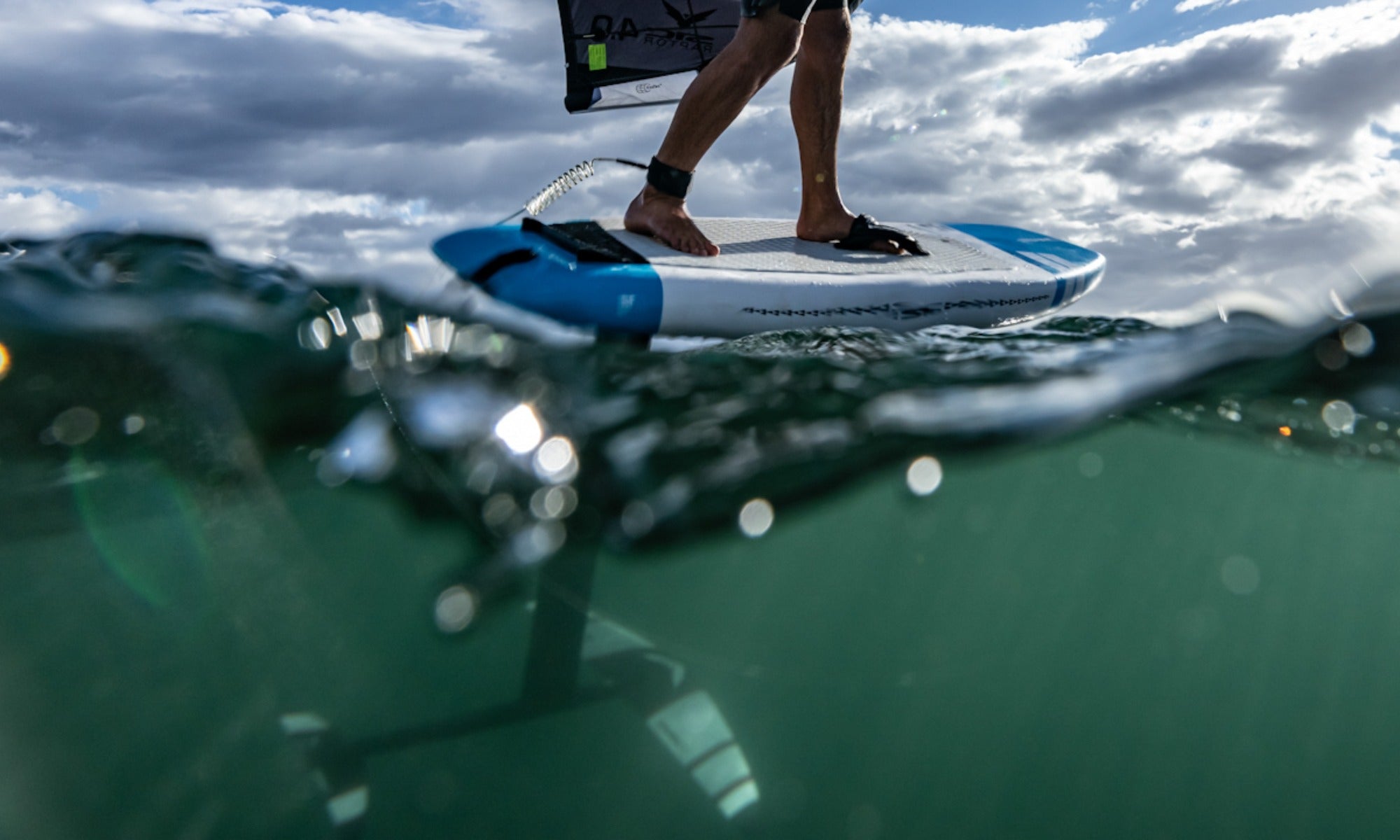 Under and over water view of a SIC Maui wing foil board during a dynamic ocean session.