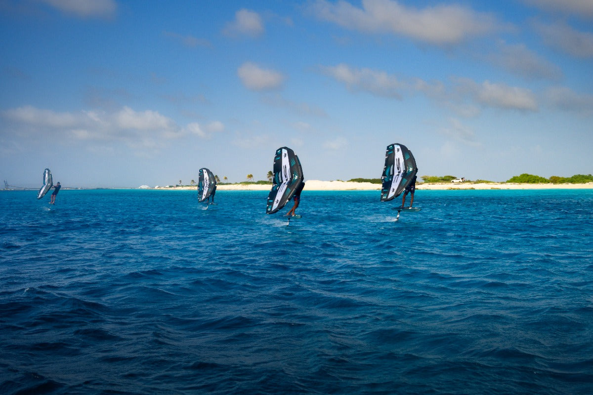 Action shot of a group of wing foilers on SIC Maui equipment near a natural island during a training session.